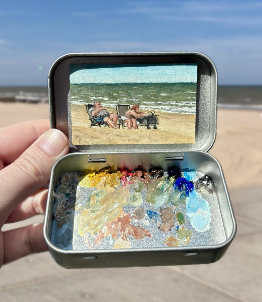 Blikvanger miniatuur schilderij in blikje met bijbehorende originele palet van twee dikke mensen die op strandstoelen zitten op het strand met zee in achtergrond